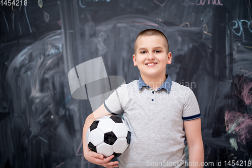 Image of happy boy holding a soccer ball in front of chalkboard