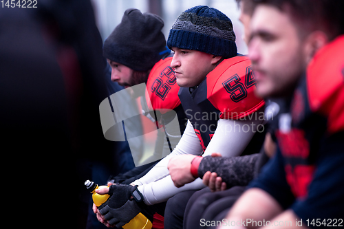 Image of american football player resting with teammates