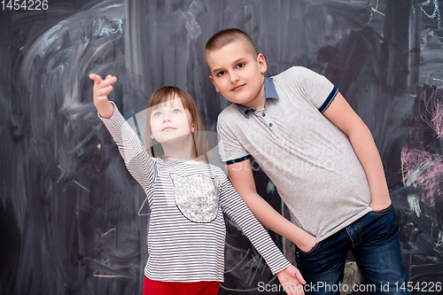 Image of boy and little girl standing in front of chalkboard