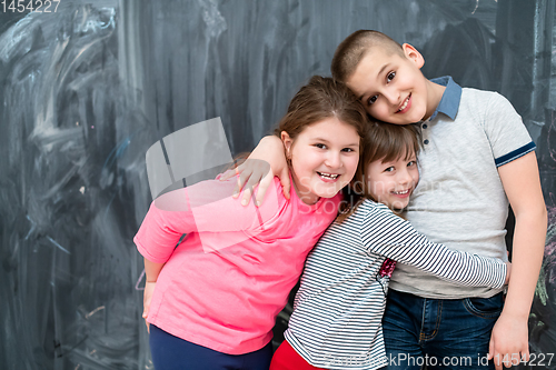 Image of group of kids hugging in front of chalkboard