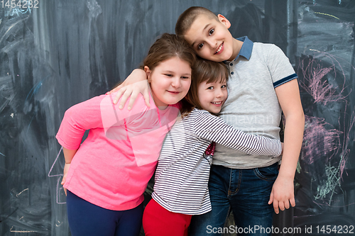 Image of group of kids hugging in front of chalkboard