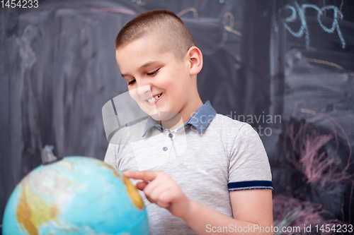 Image of boy using globe of earth in front of chalkboard