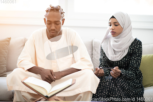 Image of african couple at home reading quaran