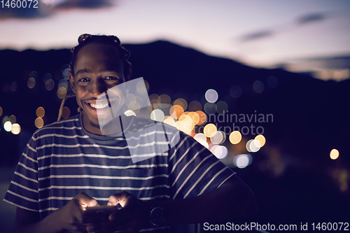 Image of Young  Afro man on  street at night using phone