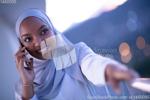 Image of Young Muslim woman on  street at night using phone