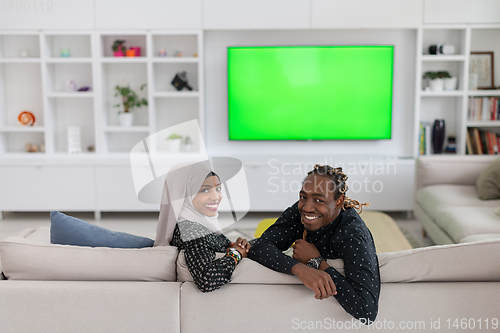 Image of African Couple Sitting On Sofa Watching TV Together