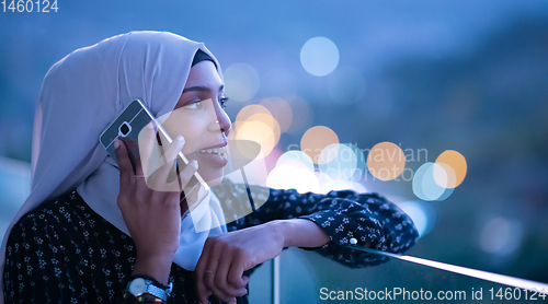 Image of Young Muslim woman on  street at night using phone