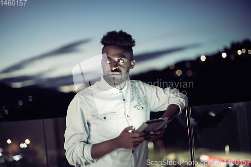 Image of Young  Afro man on  street at night using phone