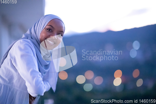 Image of African  modern Muslim woman in night at balcony