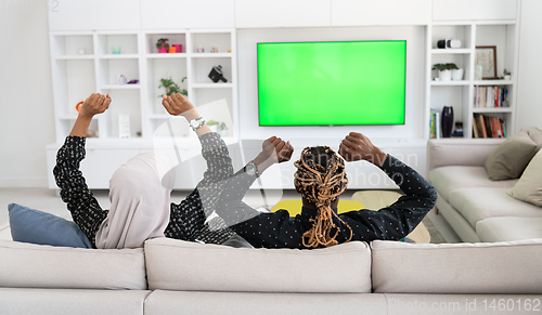 Image of African Couple Sitting On Sofa Watching TV Together