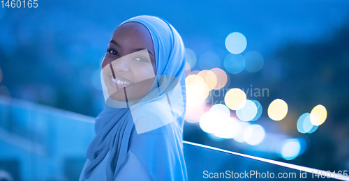 Image of African  modern Muslim woman in night at balcony