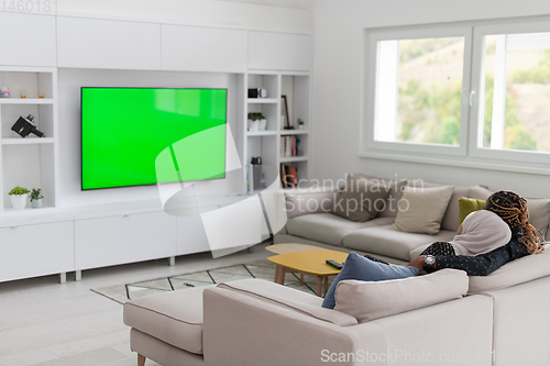 Image of African Couple Sitting On Sofa Watching TV Together