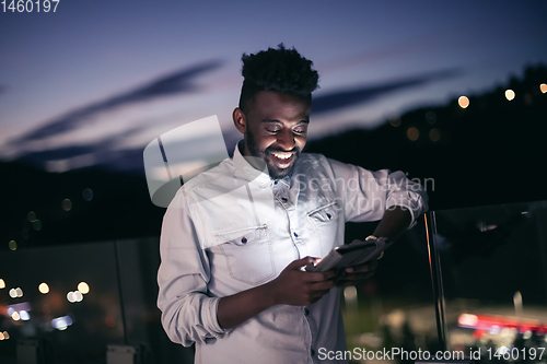 Image of Young  Afro man on  street at night using phone