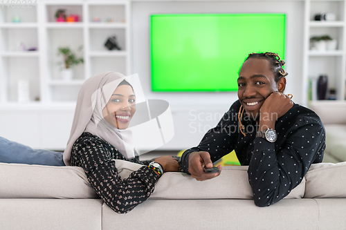 Image of African Couple Sitting On Sofa Watching TV Together