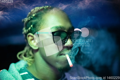 Image of african american man smiking cigarette  at nigth