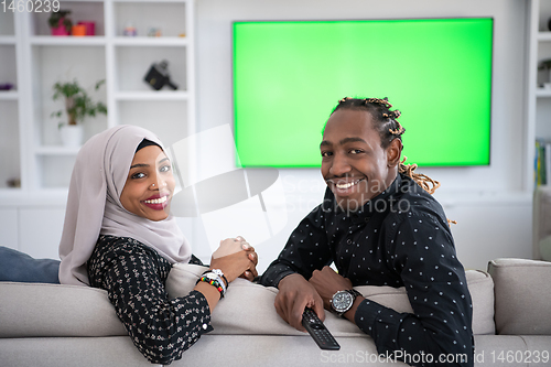 Image of African Couple Sitting On Sofa Watching TV Together