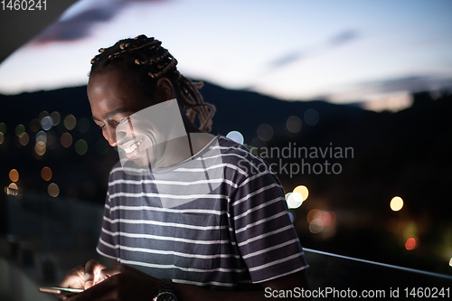 Image of Young  Afro man on  street at night using phone