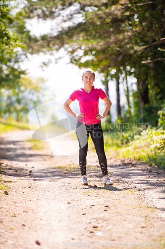 Image of portrait of young woman jogging on sunny day at nature