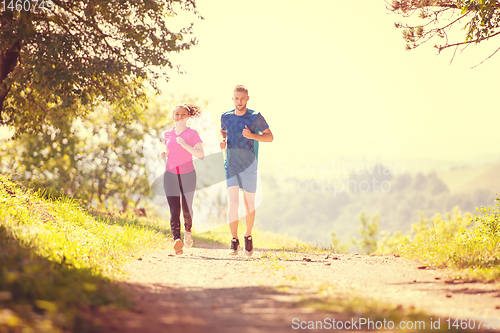 Image of young couple jogging on sunny day at nature