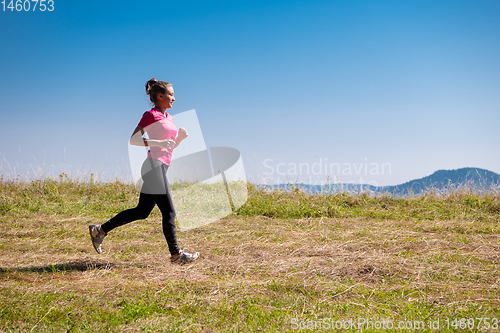 Image of young woman jogging on sunny day at summer mountain