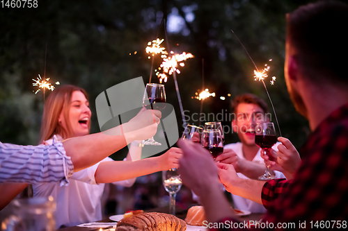 Image of happy friends having french dinner party outdoor