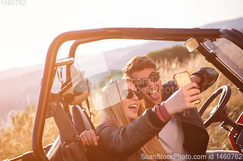 Image of young couple taking selfie picture while driving a off road bugg