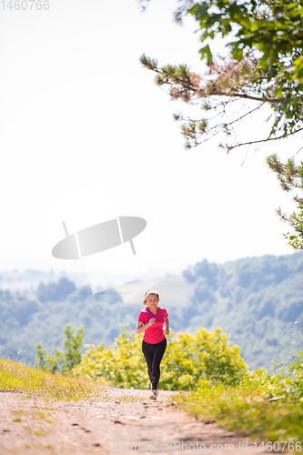 Image of young woman jogging on sunny day at nature