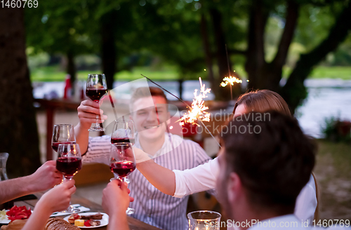 Image of happy friends having french dinner party outdoor