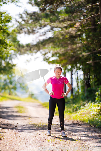 Image of portrait of young woman jogging on sunny day at nature
