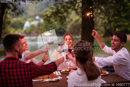 Image of happy friends having french dinner party outdoor