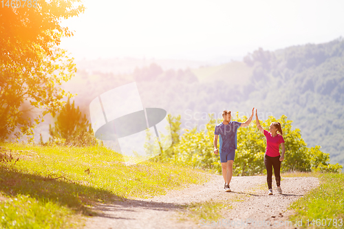 Image of jogging couple giving high five to each other on sunny day at na