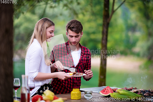 Image of happy couple having picnic french dinner party outdoor