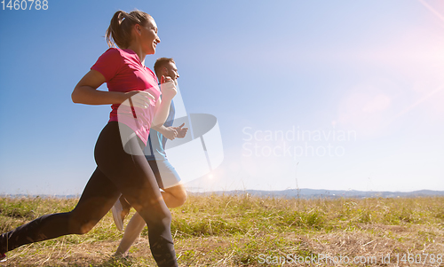 Image of young couple jogging on sunny day at summer mountain