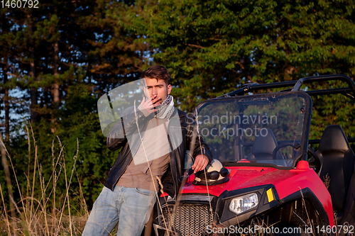 Image of young man taking a break from driving a off road buggy car