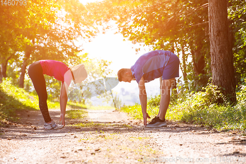 Image of young couple warming up and stretching on sunny day at nature
