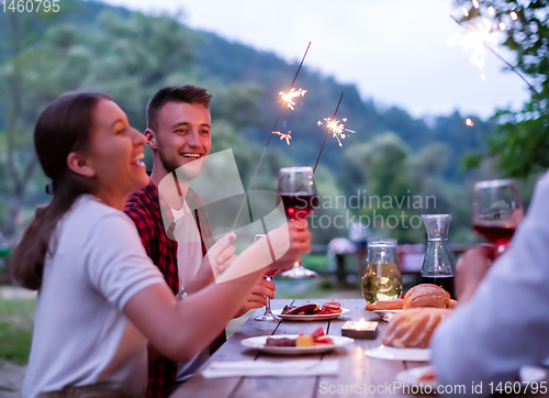 Image of happy friends having french dinner party outdoor