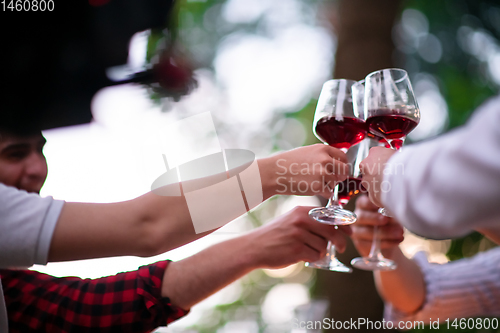 Image of happy friends toasting red wine glass during french dinner party