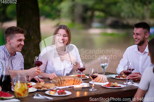 Image of happy friends having picnic french dinner party outdoor