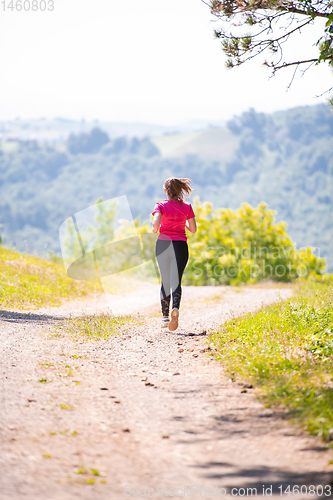 Image of young woman jogging on sunny day at nature