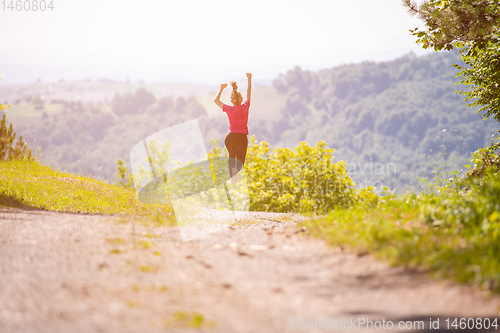 Image of young woman jogging on sunny day at nature