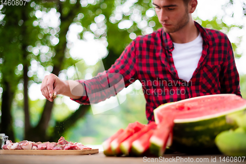 Image of Man putting spices on raw meat  for barbecue grill