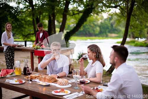 Image of happy friends having picnic french dinner party outdoor