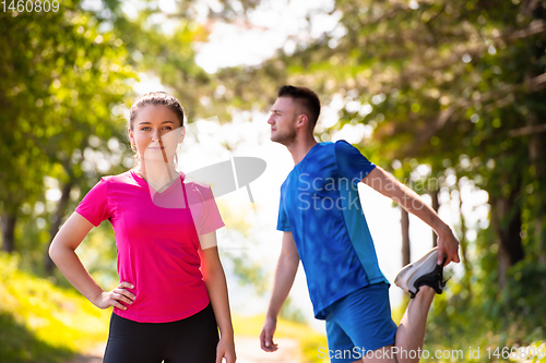 Image of young couple warming up and stretching on sunny day at nature