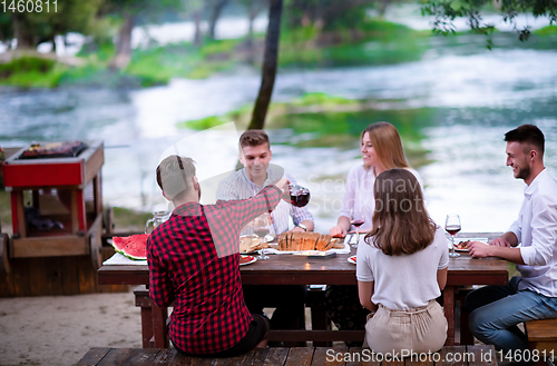 Image of happy friends having picnic french dinner party outdoor