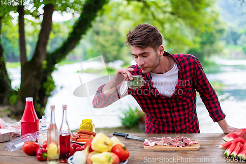 Image of Man putting spices on raw meat  for barbecue grill