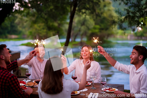 Image of happy friends having french dinner party outdoor