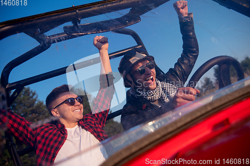 Image of two young men driving a off road buggy car