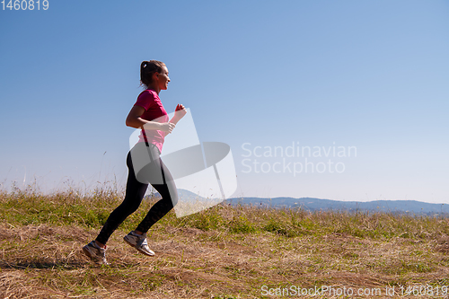 Image of young woman jogging on sunny day at summer mountain