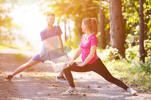 Image of young couple warming up and stretching on sunny day at nature