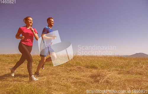 Image of young couple jogging on sunny day at summer mountain